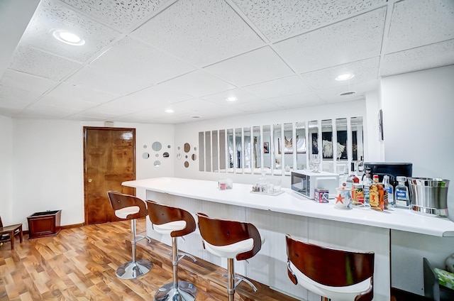 bar with hardwood / wood-style floors and a drop ceiling