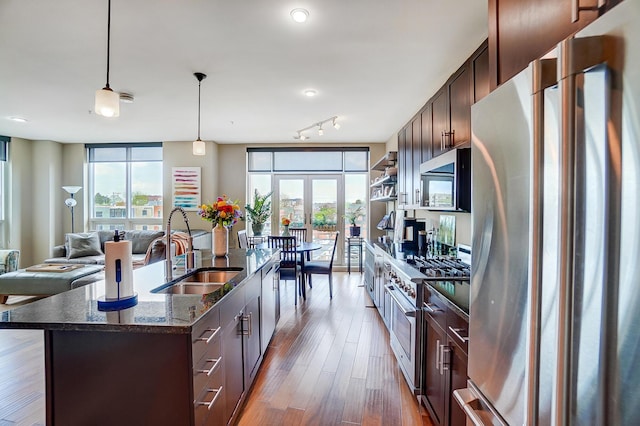 kitchen featuring appliances with stainless steel finishes, dark brown cabinetry, an island with sink, and sink