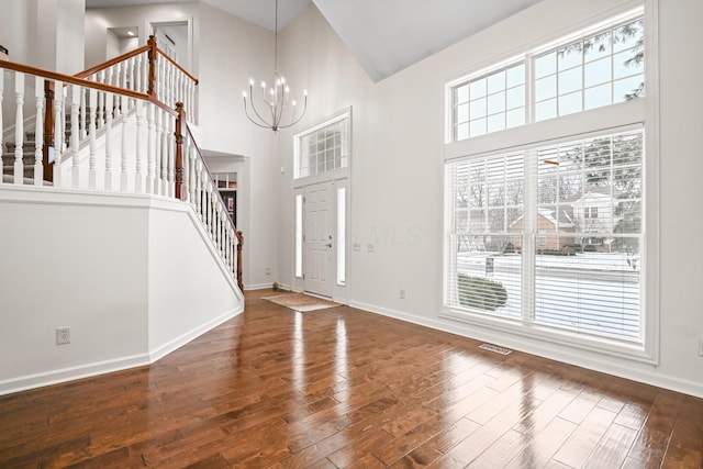 entryway featuring a notable chandelier, a towering ceiling, and wood-type flooring