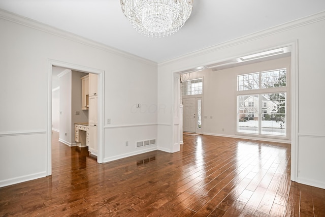 empty room featuring an inviting chandelier, ornamental molding, and dark hardwood / wood-style floors