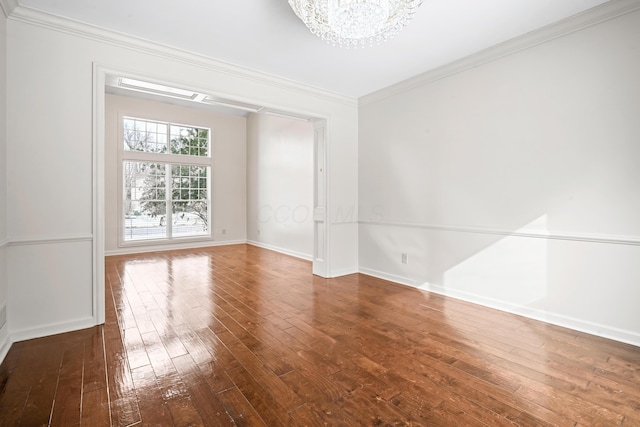 empty room with hardwood / wood-style flooring, ornamental molding, and a chandelier