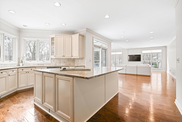 kitchen with light stone counters, backsplash, wood-type flooring, and a kitchen island