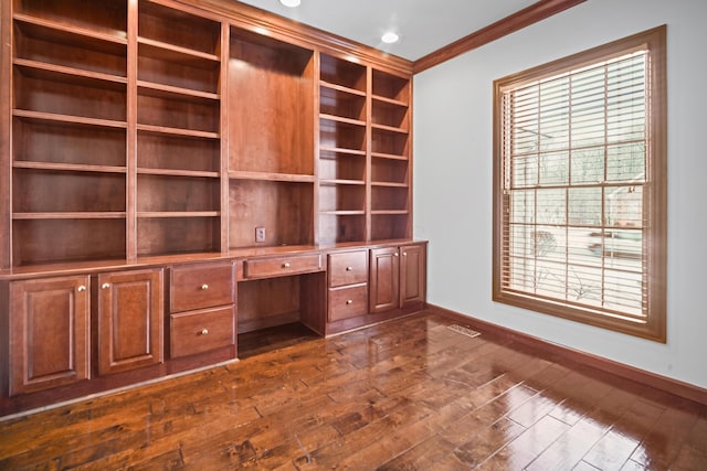 unfurnished office with dark hardwood / wood-style flooring, built in desk, and ornamental molding