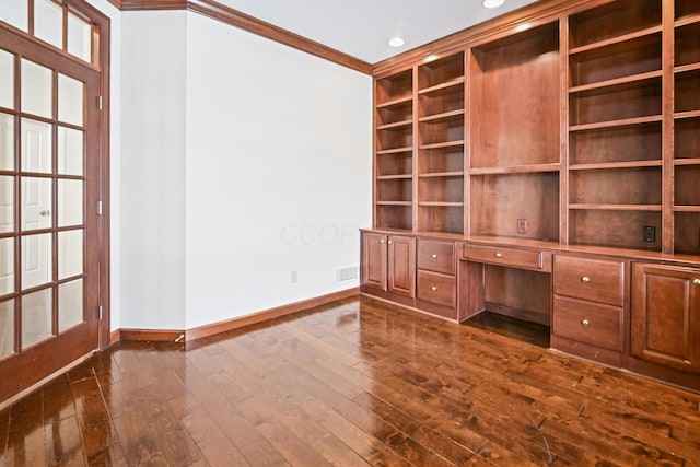 unfurnished office featuring built in features, built in desk, ornamental molding, and dark hardwood / wood-style floors