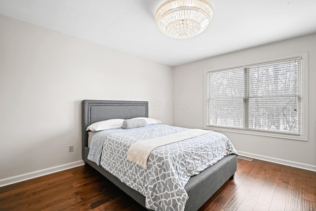 bedroom with an inviting chandelier and dark hardwood / wood-style floors