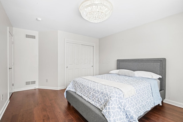 bedroom featuring a notable chandelier, dark wood-type flooring, and a closet