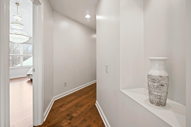 corridor featuring dark wood-type flooring and a notable chandelier