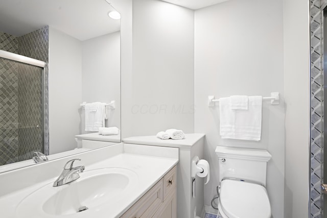 bathroom with vanity, toilet, and a shower with door