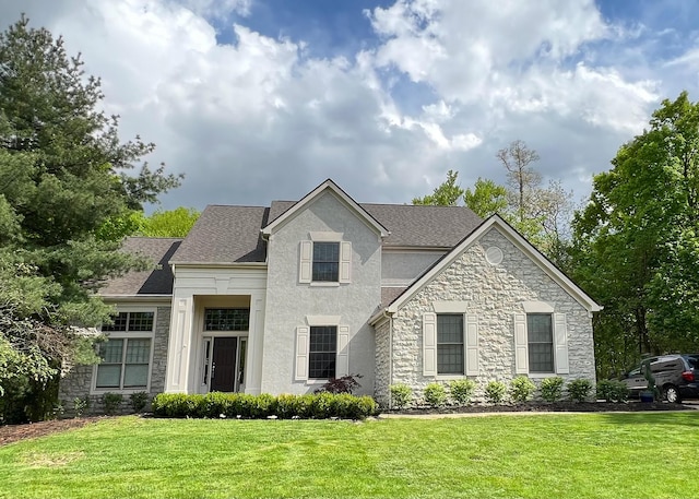 view of front of property featuring a shingled roof, stucco siding, a front yard, and stone siding