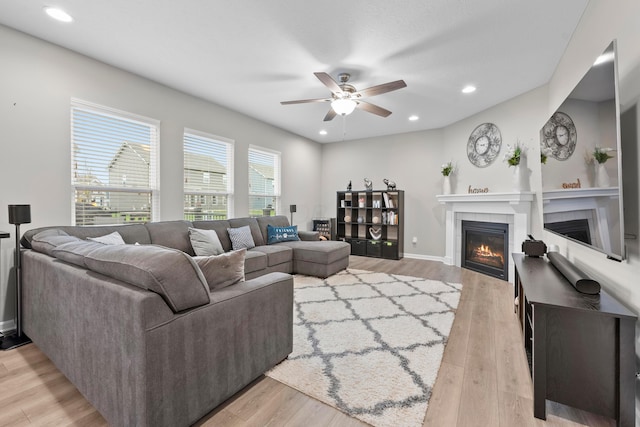 living room with ceiling fan, a fireplace, and light hardwood / wood-style flooring