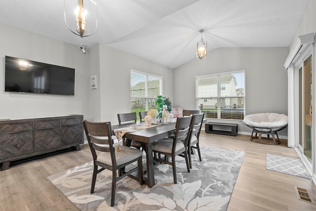 dining room featuring light hardwood / wood-style flooring, lofted ceiling, and an inviting chandelier