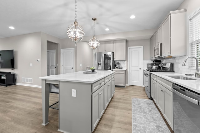 kitchen with appliances with stainless steel finishes, backsplash, sink, pendant lighting, and a kitchen island