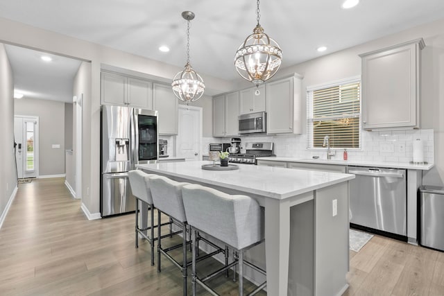 kitchen with sink, decorative backsplash, decorative light fixtures, a kitchen island, and stainless steel appliances