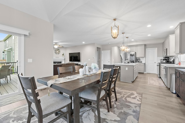 dining area featuring light hardwood / wood-style floors and ceiling fan with notable chandelier