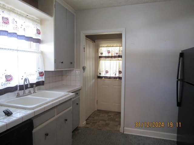 kitchen featuring tasteful backsplash, a wealth of natural light, sink, black appliances, and tile countertops