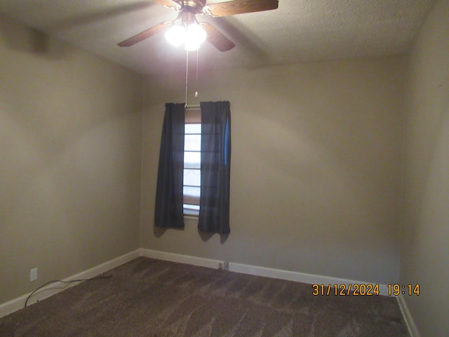 spare room featuring ceiling fan, a textured ceiling, and dark colored carpet