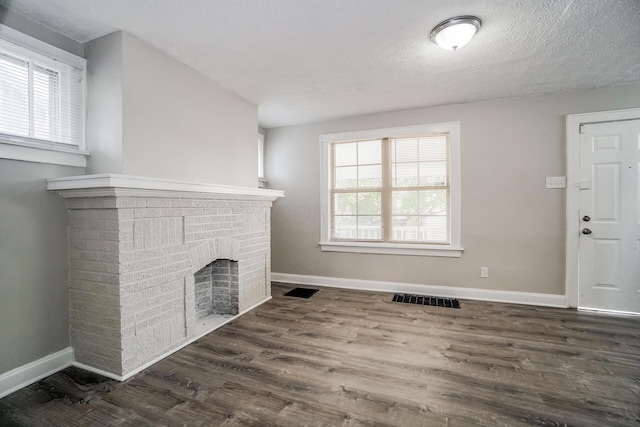 unfurnished living room featuring a textured ceiling, a fireplace, and dark wood-type flooring