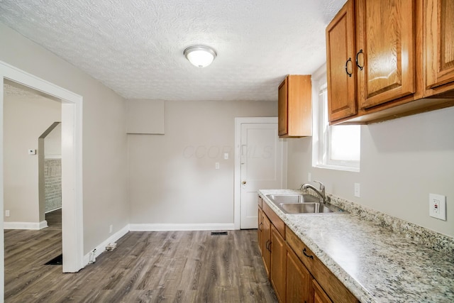 kitchen with light stone counters, sink, a textured ceiling, and hardwood / wood-style flooring