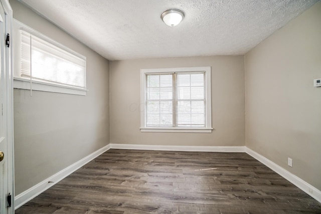 spare room with a textured ceiling and dark wood-type flooring