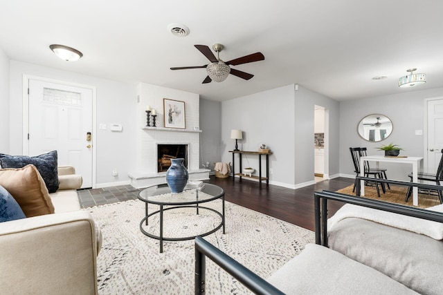 living room with dark hardwood / wood-style floors, a brick fireplace, and ceiling fan