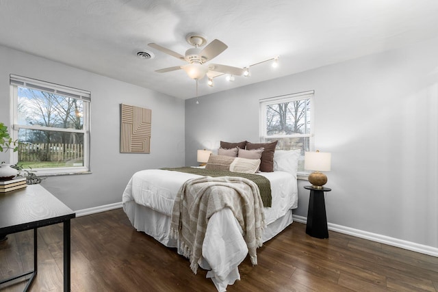 bedroom with multiple windows, ceiling fan, and dark wood-type flooring