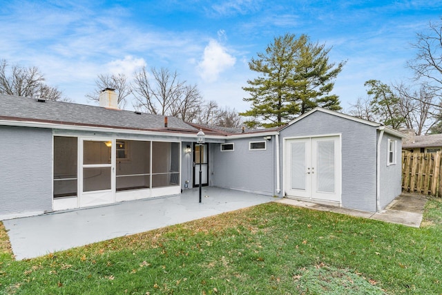 back of property featuring a lawn, a sunroom, and a patio