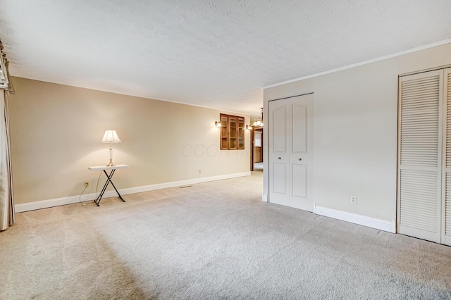 carpeted spare room featuring a textured ceiling and ornamental molding