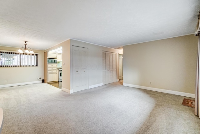 carpeted spare room featuring an inviting chandelier