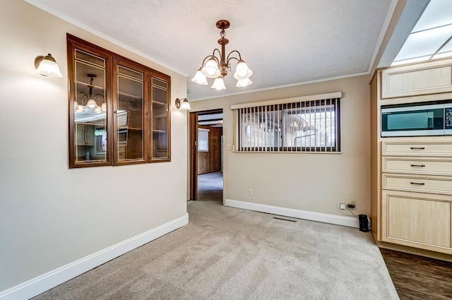 unfurnished dining area with crown molding, light colored carpet, and an inviting chandelier