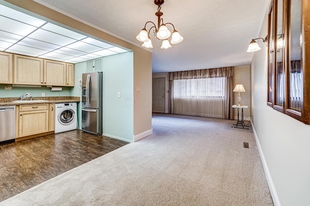 kitchen with pendant lighting, dark carpet, an inviting chandelier, washer / dryer, and stainless steel appliances