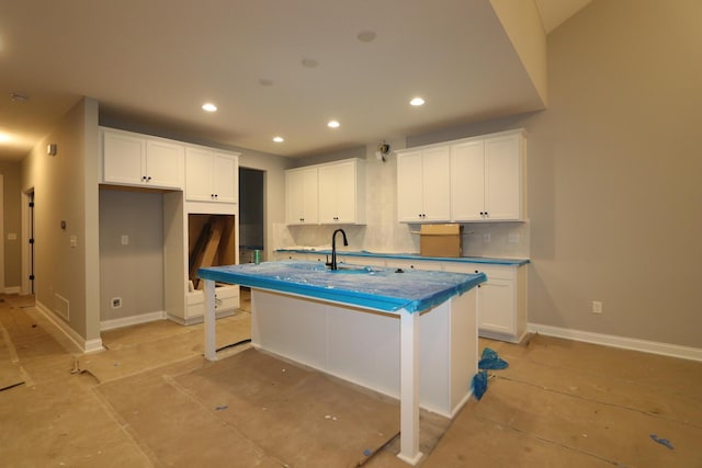 kitchen with tasteful backsplash, a kitchen island with sink, a breakfast bar area, and white cabinets