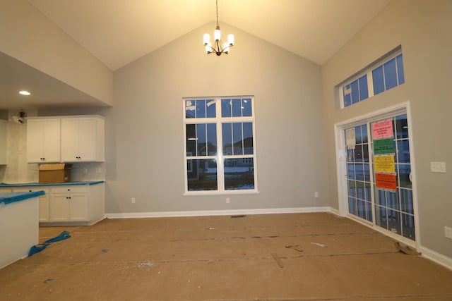 unfurnished dining area with an inviting chandelier and high vaulted ceiling