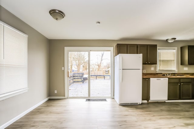 kitchen featuring dark brown cabinets, light wood-type flooring, white appliances, and sink