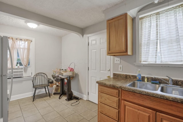 kitchen with a textured ceiling, white fridge, and sink