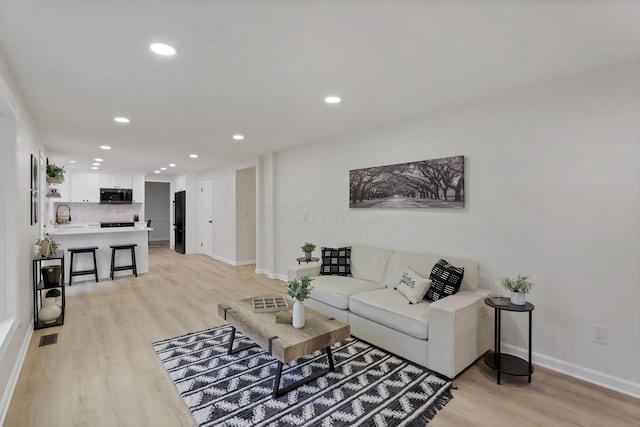 living room featuring light wood-type flooring and sink