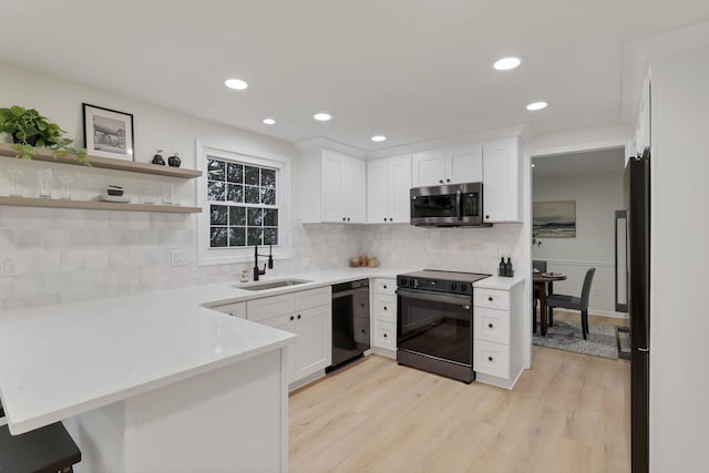 kitchen with decorative backsplash, kitchen peninsula, sink, black appliances, and white cabinets