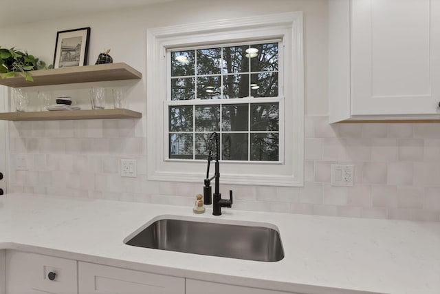 kitchen featuring white cabinets, light stone counters, sink, and tasteful backsplash