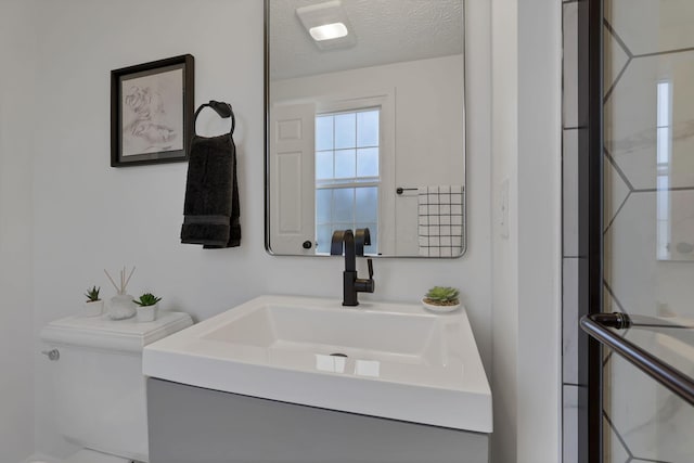 bathroom featuring vanity, toilet, and a textured ceiling