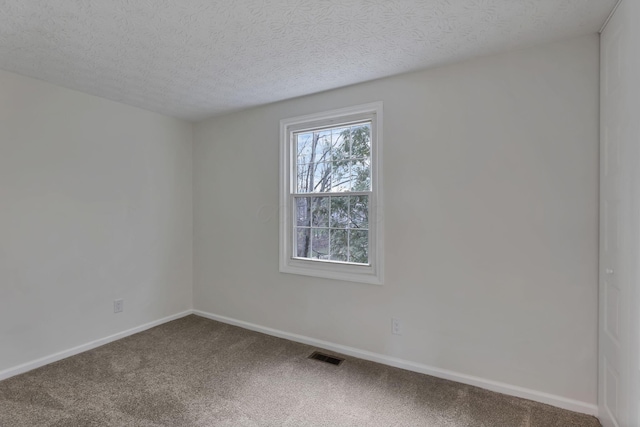 carpeted empty room with a textured ceiling