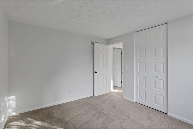 unfurnished bedroom with a closet, light colored carpet, and a textured ceiling