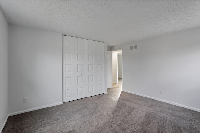 unfurnished bedroom featuring carpet flooring, a textured ceiling, and a closet