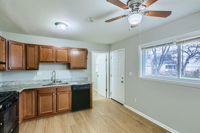 kitchen with sink, ceiling fan, black appliances, light stone countertops, and light wood-type flooring