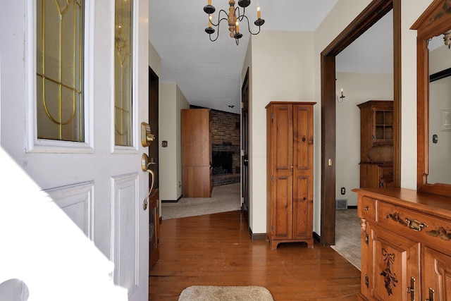 foyer entrance with dark hardwood / wood-style floors, a chandelier, and a fireplace