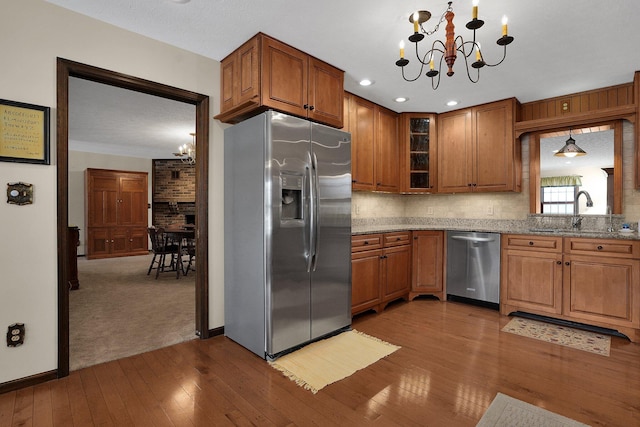 kitchen featuring hanging light fixtures, light stone countertops, appliances with stainless steel finishes, and sink