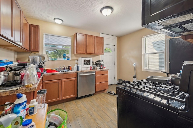 kitchen with stainless steel dishwasher, a textured ceiling, exhaust hood, sink, and light hardwood / wood-style flooring