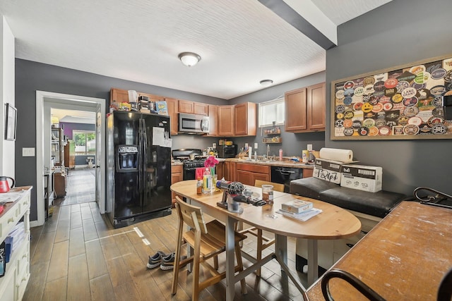 kitchen with black appliances, plenty of natural light, sink, and a textured ceiling