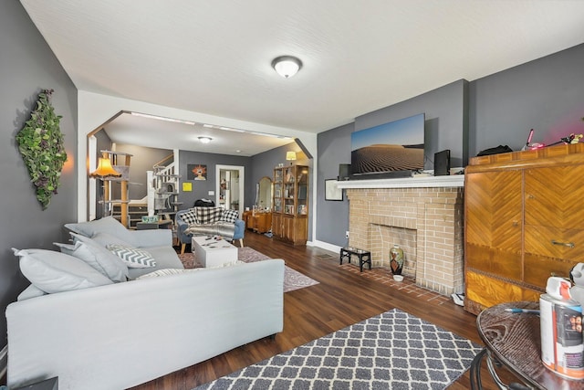 living room with dark hardwood / wood-style flooring and a brick fireplace