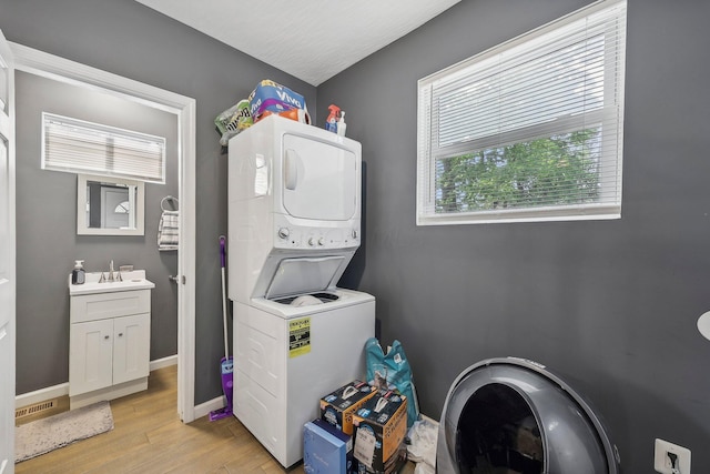 laundry area featuring stacked washer and dryer and light hardwood / wood-style flooring