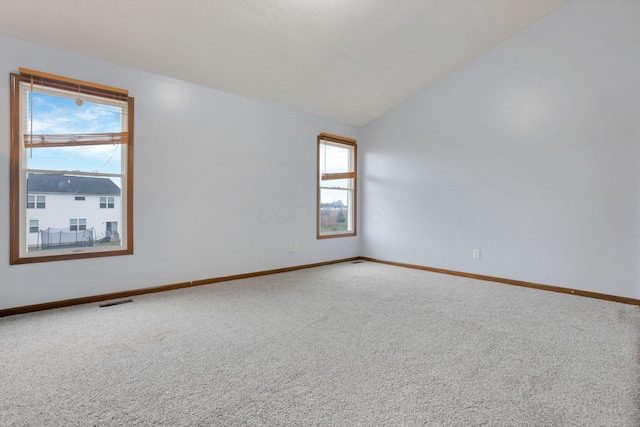 spare room featuring carpet and lofted ceiling