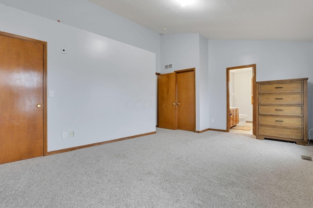 unfurnished bedroom with connected bathroom, a closet, light colored carpet, and lofted ceiling